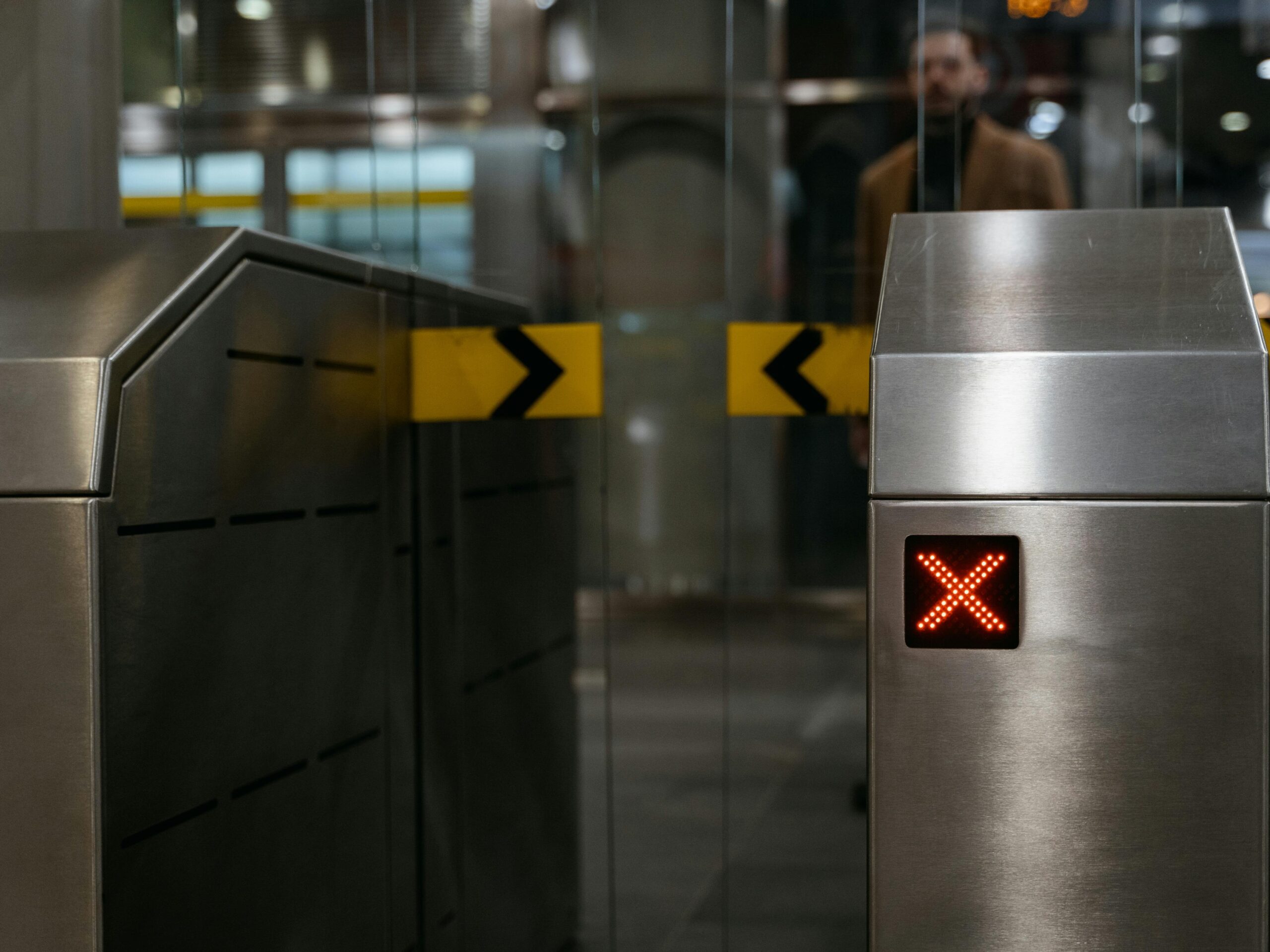Close-up of a stainless steel ticket barrier with red X signal indicating no entry.